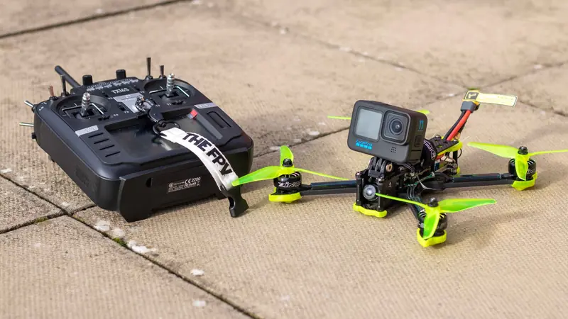 Close-up of FPV drone with action camera and controller on outdoor pavement, ready for flight