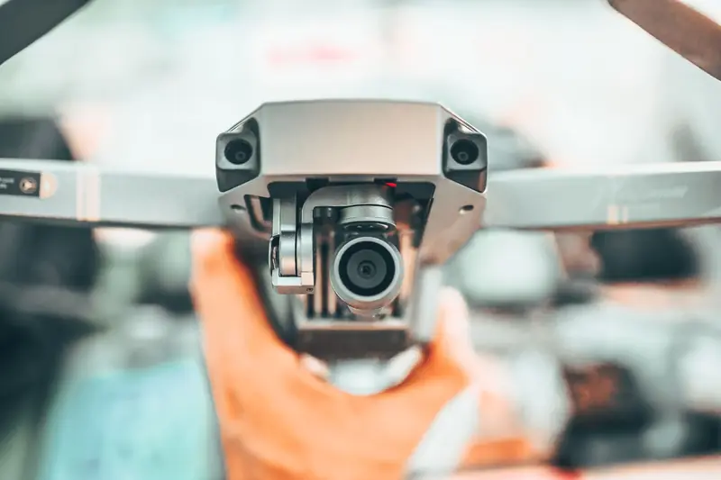 Crop unrecognizable person holding contemporary drone against blurred interior and demonstrating powerful camera