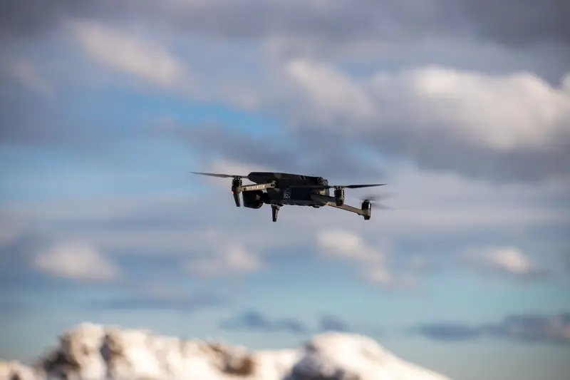Aerial view of a drone flying over snow-covered mountains with dramatic clouds