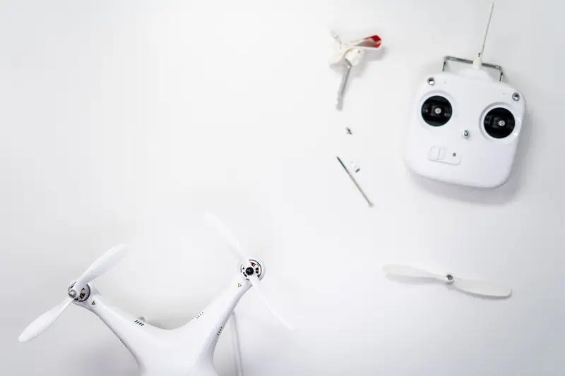 A flat lay of a drone kit including a controller and spare propellers on a white background