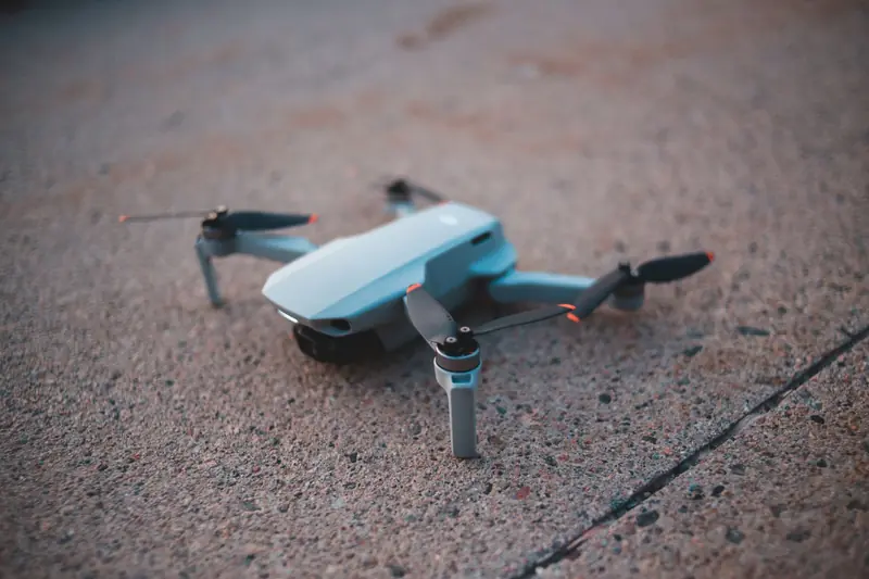 A close-up shot of a compact drone resting on a textured concrete surface, captured at dusk