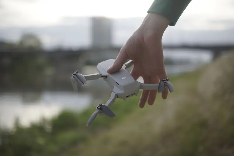 Close-up of a hand holding a small drone outdoors near a riverbank in Mannheim, Germany