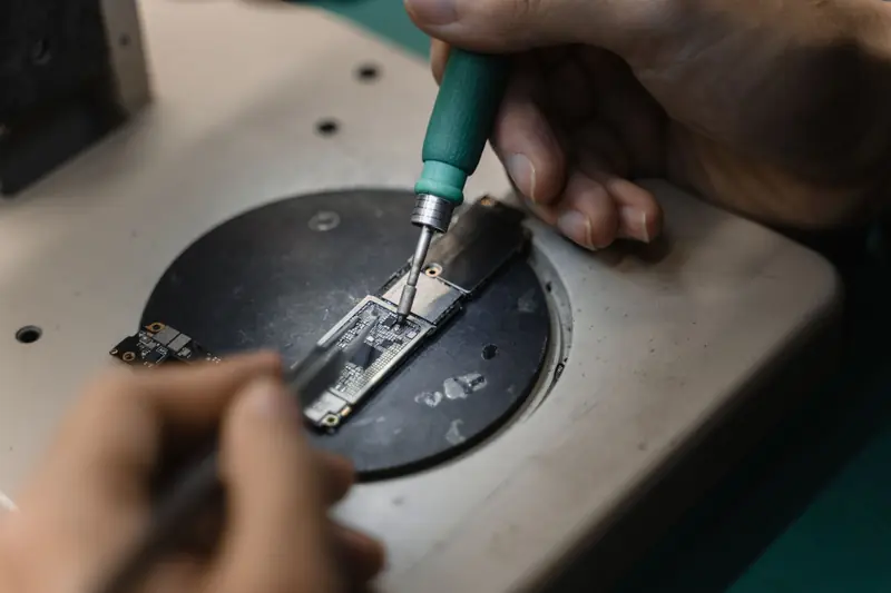 Hands using a soldering iron on circuit board, showcasing precise electronic repair indoors