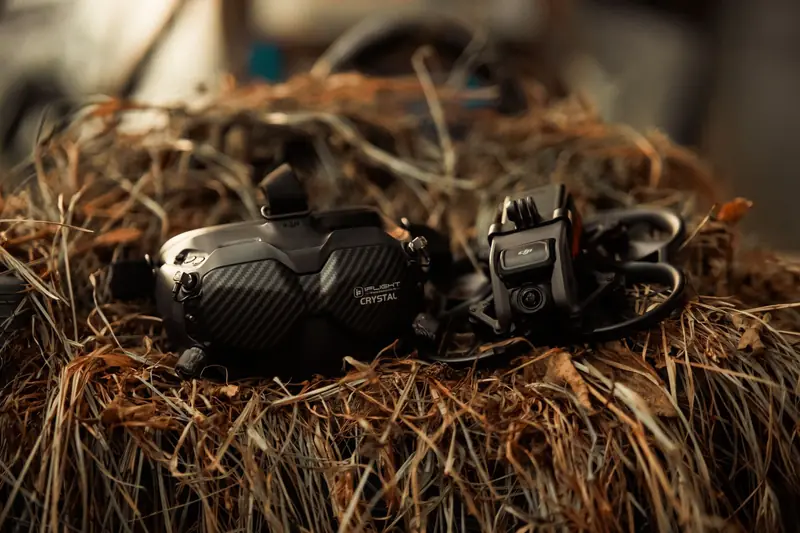 Close-up of FPV drone and goggles placed on a rustic straw surface, showcasing technology in nature