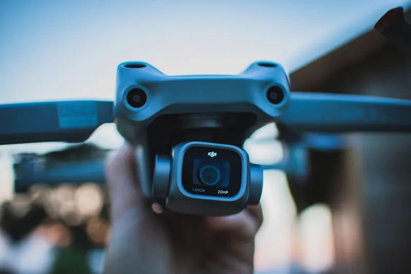 Detailed close-up of a hand holding a drone camera with blurry background, captured outdoors