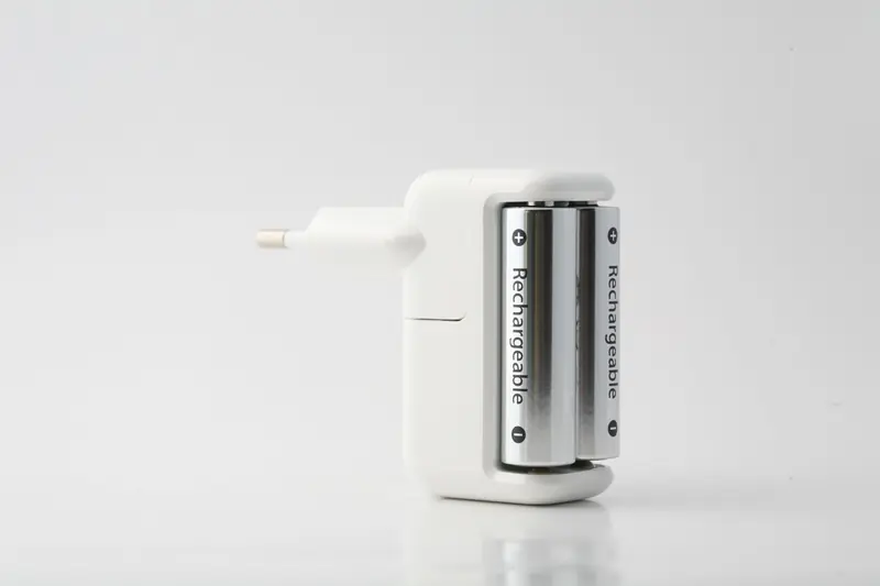Minimalist shot of a rechargeable battery charger with two batteries on a white backdrop