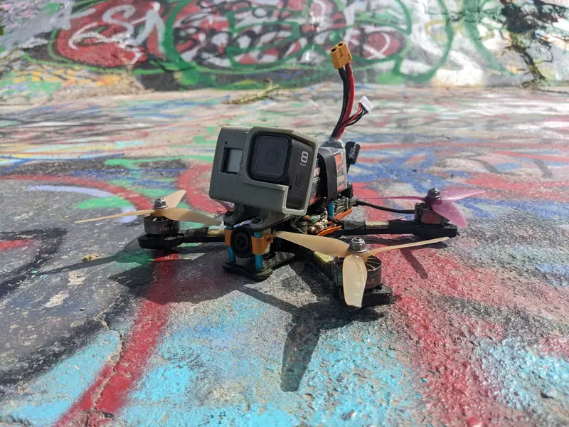 Close-up of an FPV racing drone with a camera on colorful graffiti background outdoors